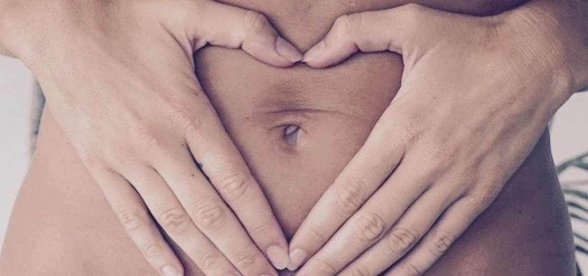 Woman's stomach with hands making a heart